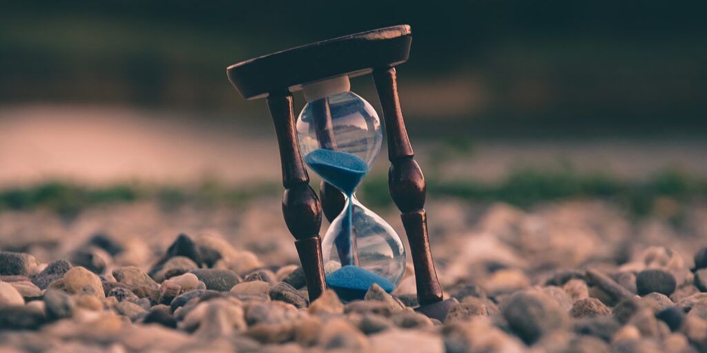 time management, selective focus photo of brown and blue hourglass on stones