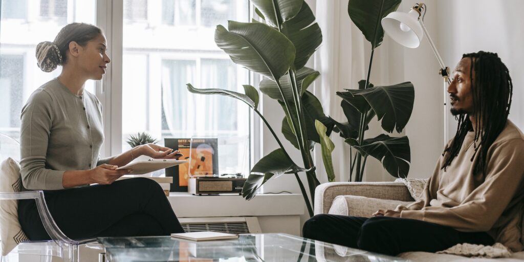 Office Condo, Side view of professional female African American therapist sitting in front of black male patient during psychotherapy session in office