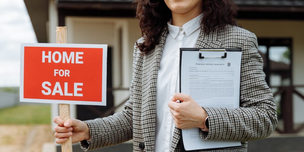 Close-up of a Woman Holding a Home For Sale Sign