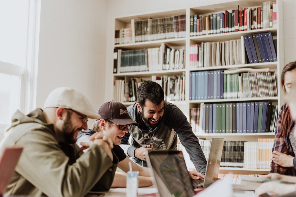 co-living, three men laughing while looking in the laptop inside room